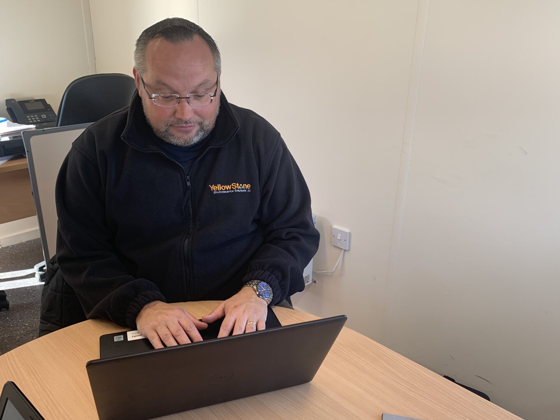 yellowstone employee sat as desk typing on laptop