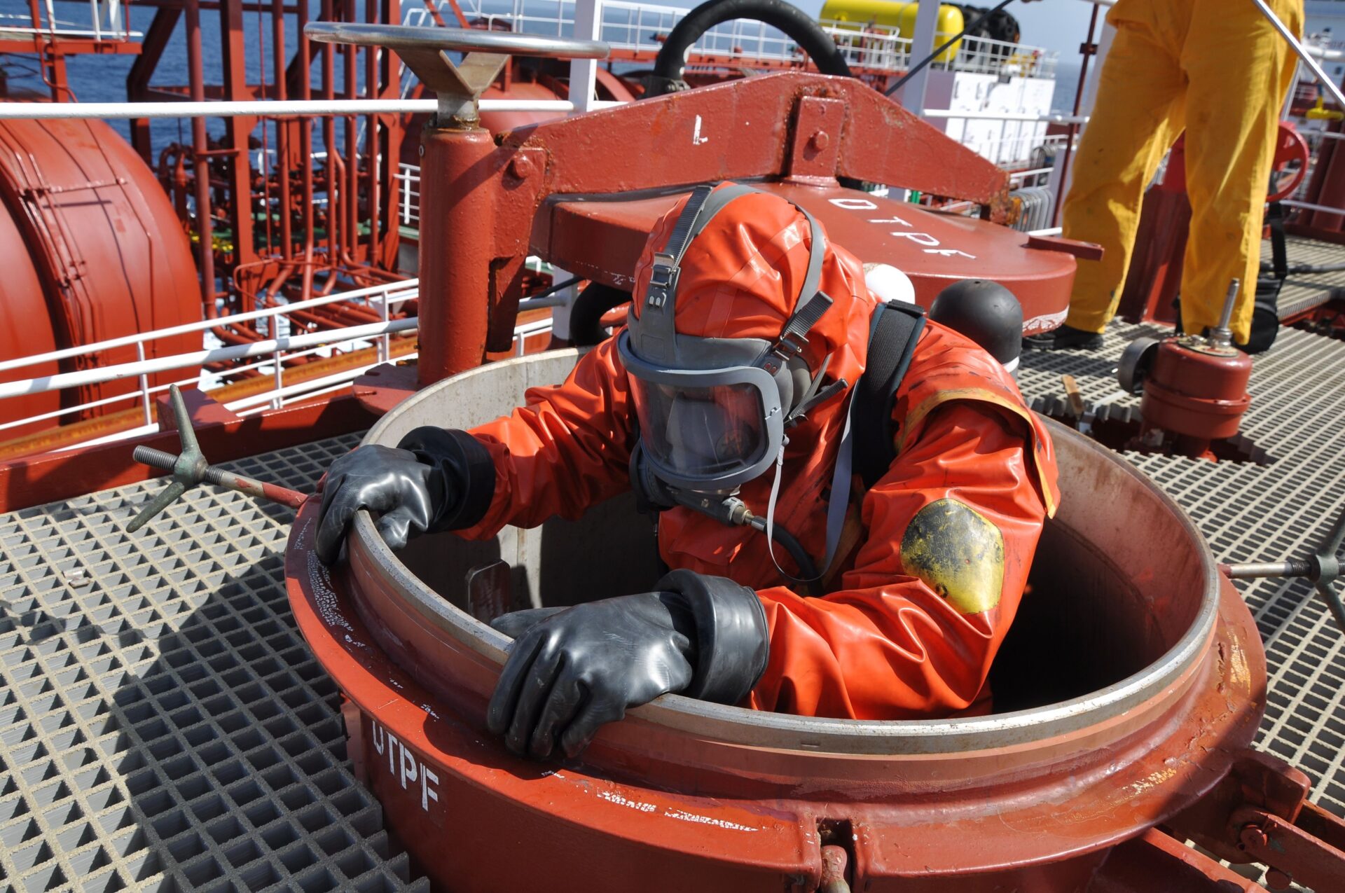 man in chemical suit entering inside cargo tank on deck of chemi